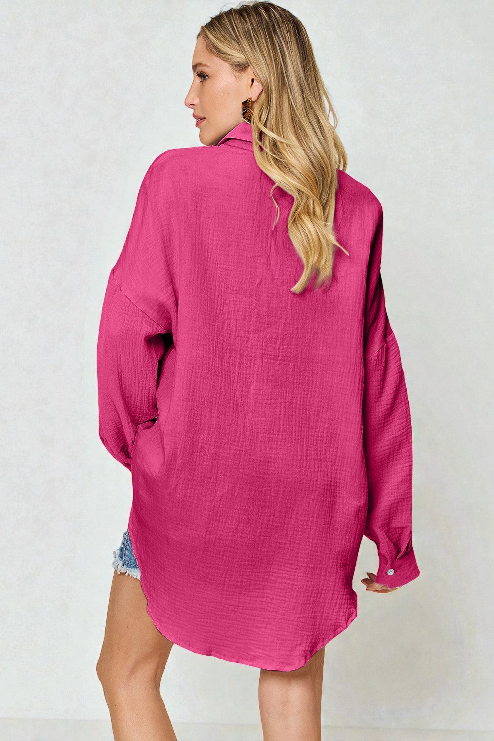 Woman wearing a pink oversized shirt against a white background