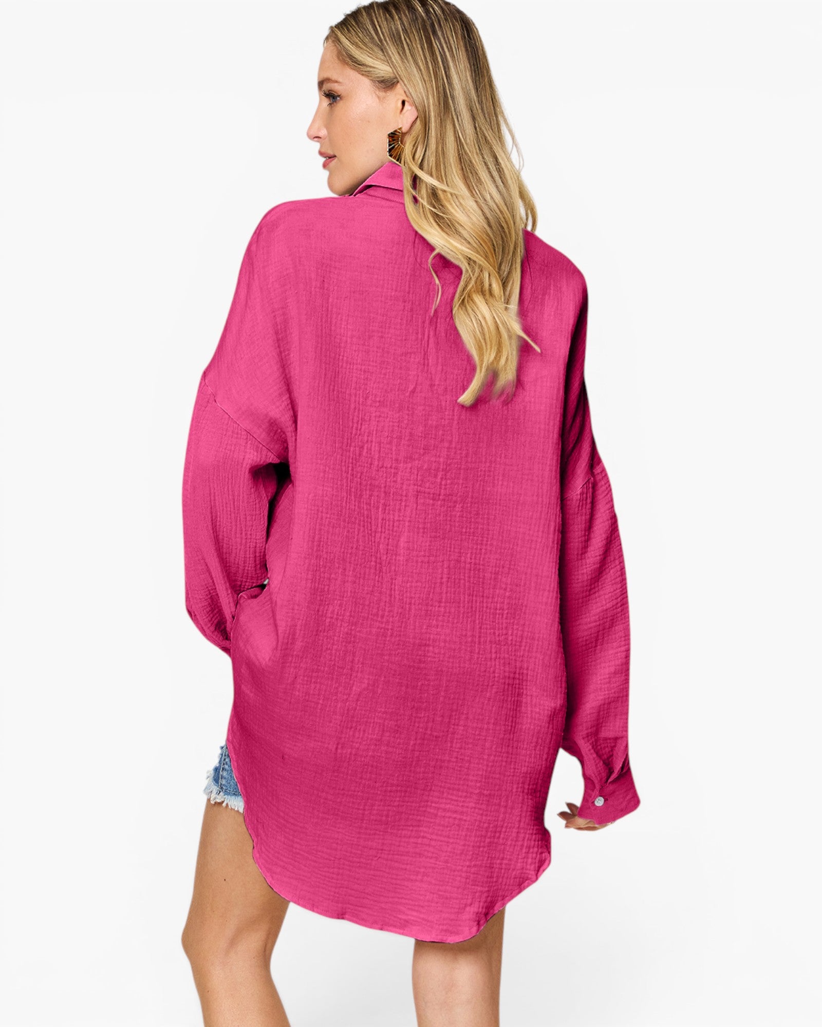 A woman shown from the back wearing a bright pink textured long-sleeve shirt over a light blue denim dress, against a plain white background.