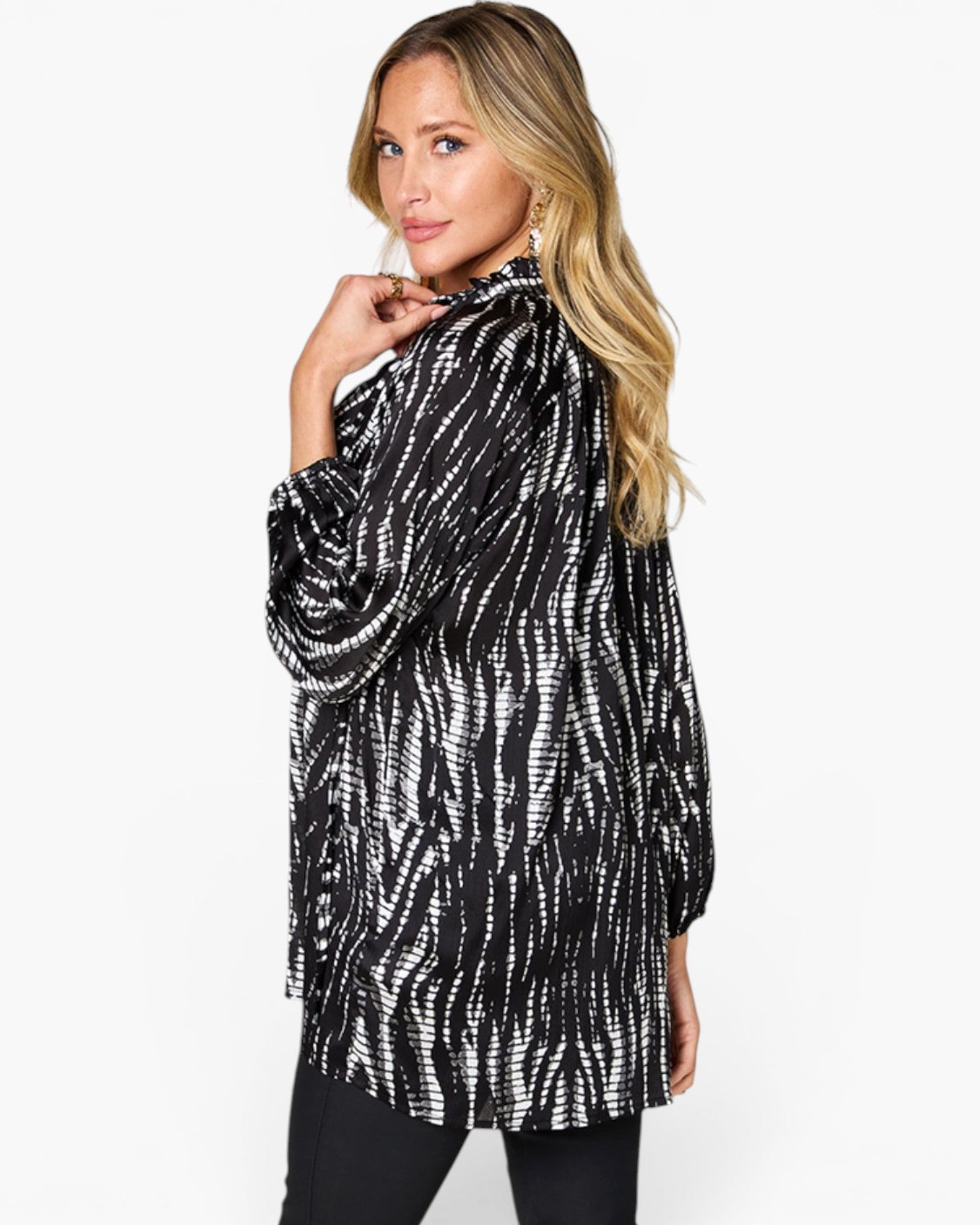 A woman modeling a black and white tie-dye patterned long-sleeve tunic top against a plain white background.