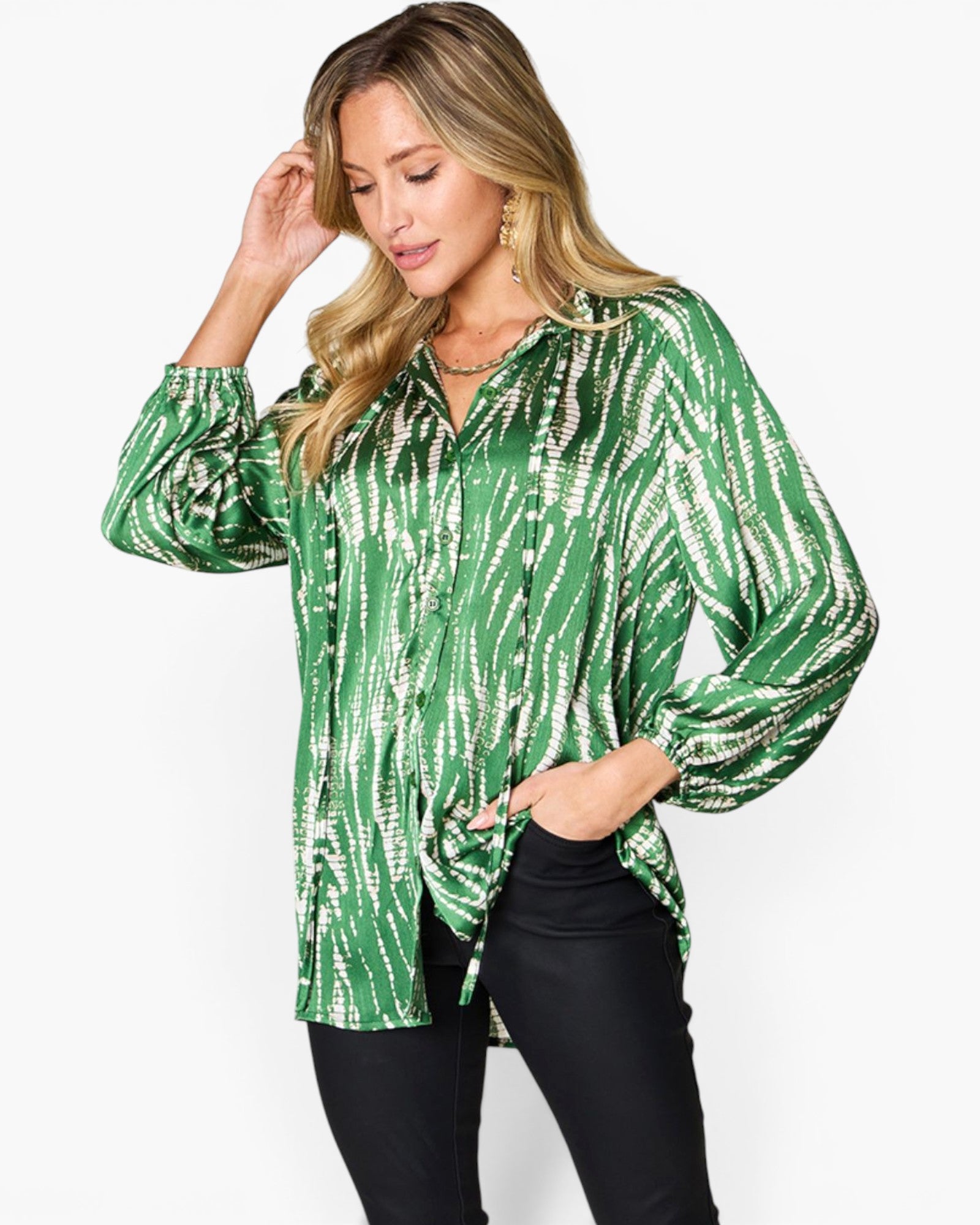 A woman modeling a green and white tie-dye patterned long-sleeve blouse with a button-down front, paired with black pants, against a plain white studio background.