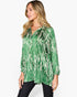 A woman wearing a green long-sleeve button-up shirt with a white tie-dye pattern, paired with black pants, photographed against a plain white background.