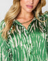 A close-up of a woman wearing a green and white tie-dye patterned button-down blouse, styled with a gold chain necklace.