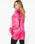 A woman wearing a bright pink and white tie-dye patterned long-sleeve top, shown from a side-back angle against a plain white studio background.