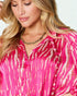 Woman wearing a pink tie-dye shirt with a plain background