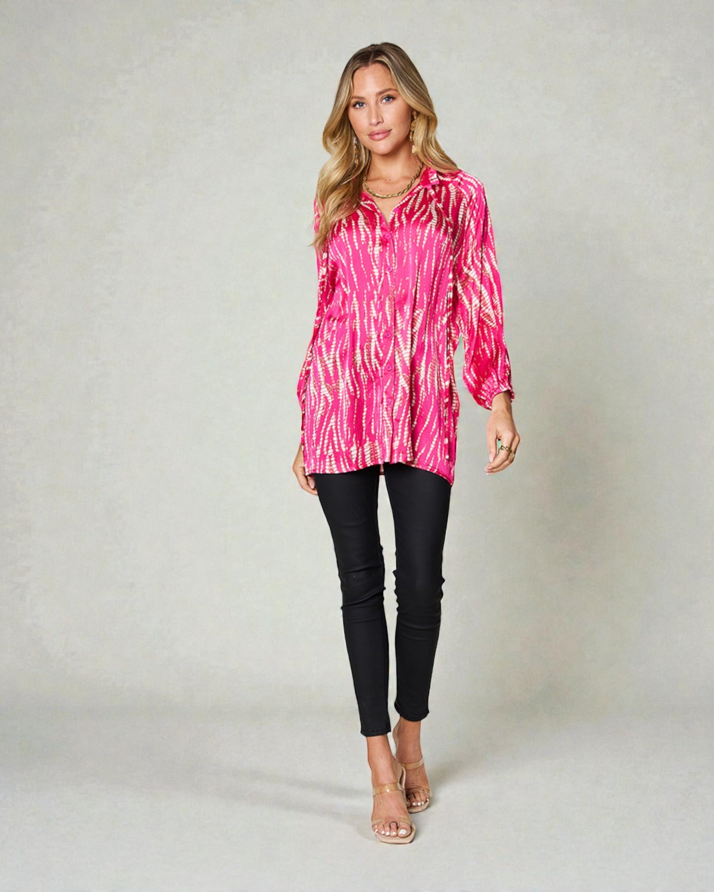 Woman wearing a pink tie-dye top and black pants on a plain background