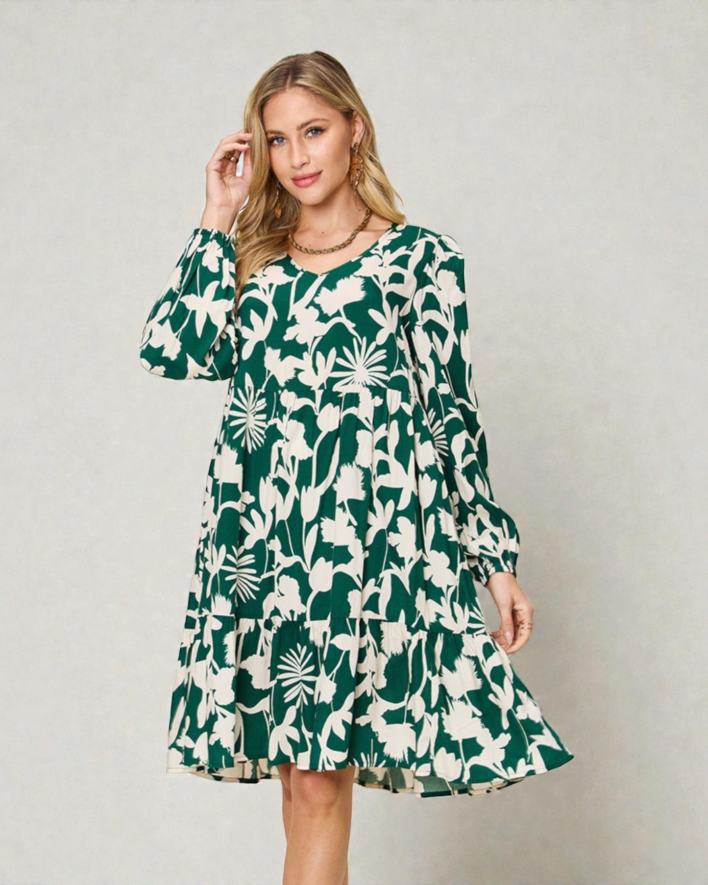 Woman wearing a green and white floral dress against a plain background