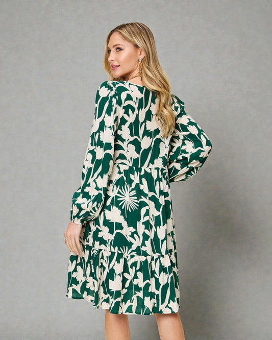 Woman wearing a green and white floral dress against a gray background