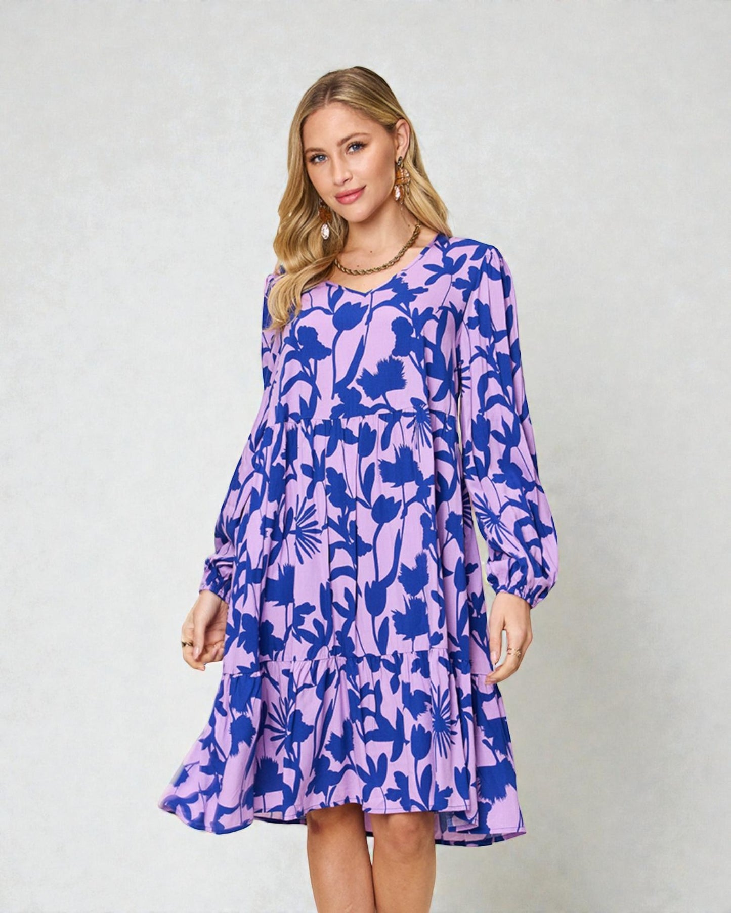 Woman wearing a purple floral dress against a plain background