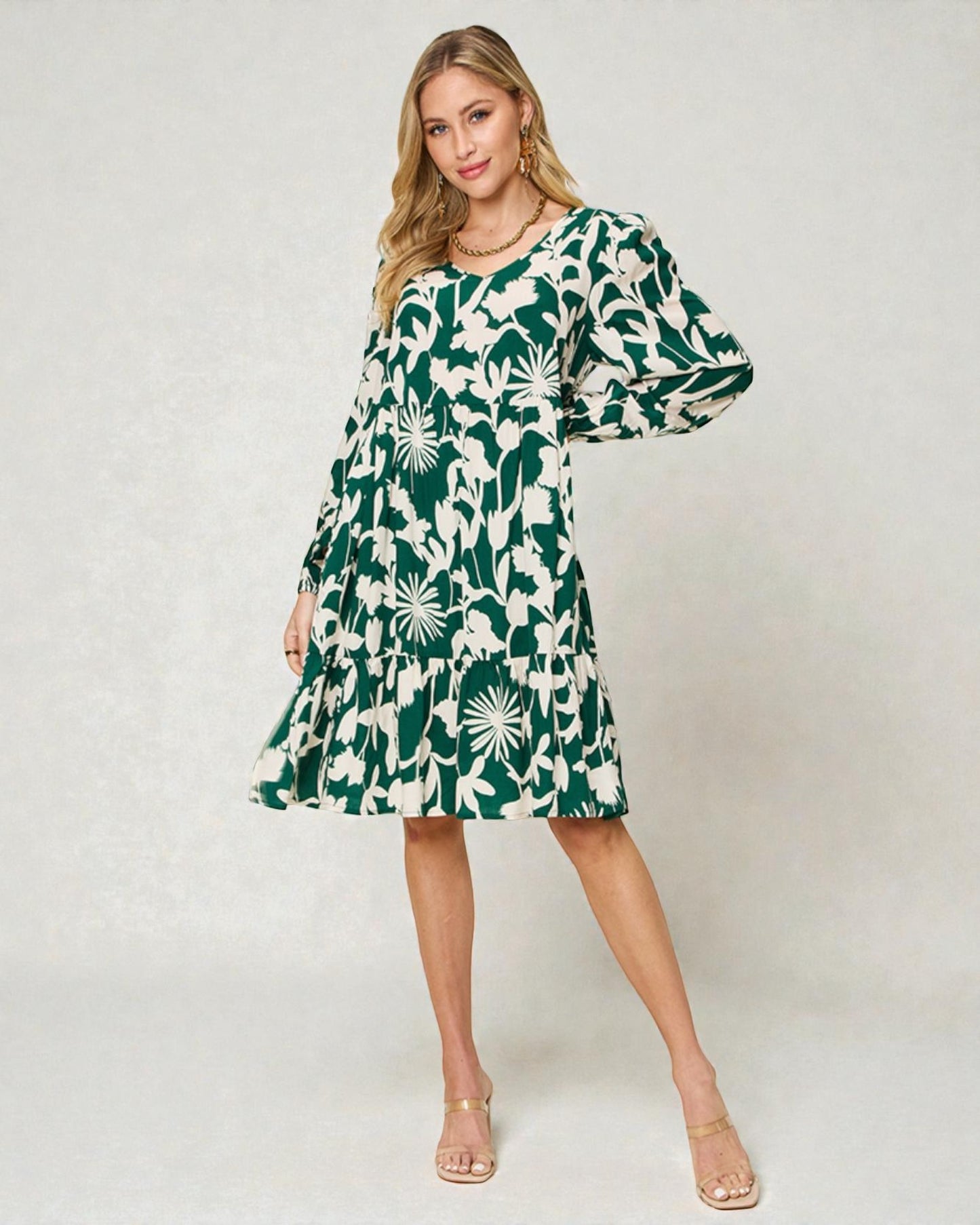 Woman wearing a green and white floral dress on a plain background