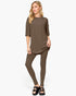 A woman modeling a matching two-piece lounge set consisting of an oversized short-sleeve top and slim-fit leggings in a solid taupe-brown color, paired with black slide sandals, against a plain white background.