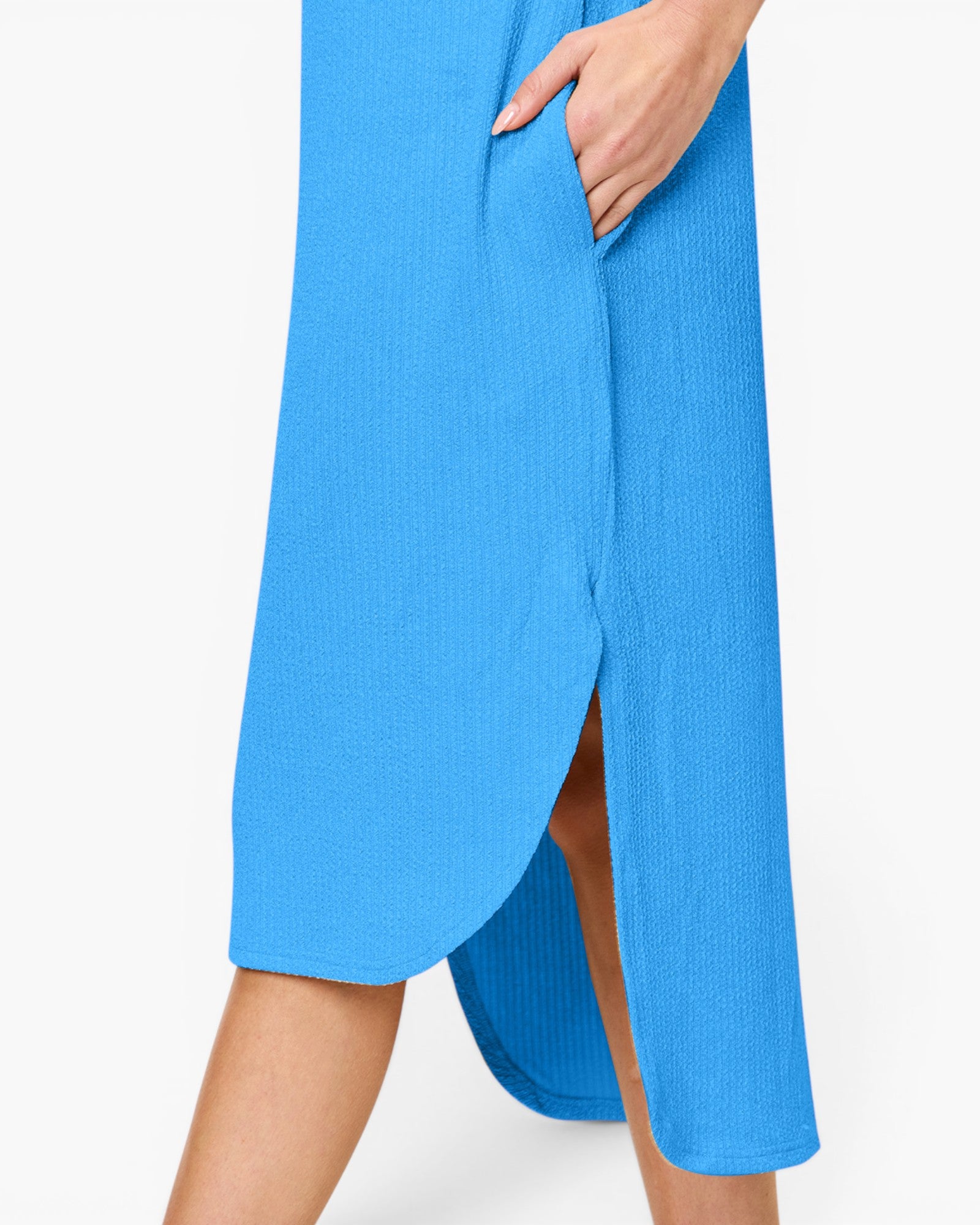 A close-up of a model wearing a bright blue ribbed midi skirt with a side slit and pocket, shown against a plain white background.