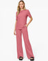 A woman modeling a dusty rose two-piece loungewear set consisting of a short-sleeve crewneck top and matching wide-leg pants, paired with black slide sandals against a plain white studio background.