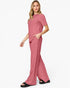 A woman modeling a dusty rose two-piece lounge set consisting of a short-sleeve top and matching wide-leg pants, paired with black slide sandals against a plain white studio background.