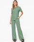 A woman modeling a sage green two-piece lounge set consisting of a short-sleeve crewneck top and matching wide-leg pants, paired with black slide sandals against a plain white studio background.
