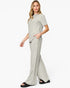 A woman modeling a light sage green two-piece lounge set consisting of a short-sleeve crewneck top and matching wide-leg pants, paired with black slide sandals against a plain white studio background.