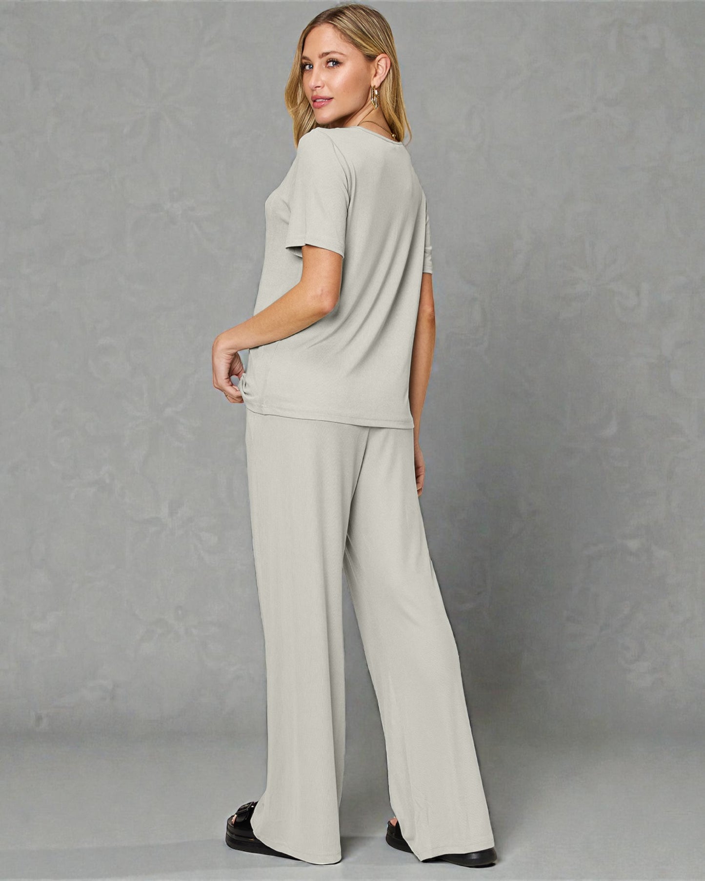 Woman wearing a light gray outfit against a plain background