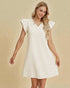 Woman wearing a white dress with ruffled sleeves on a beige background