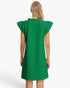 A woman viewed from the back wearing a bright green textured dress with ruffled cap sleeves and a ruffled neckline, against a clean white studio background.