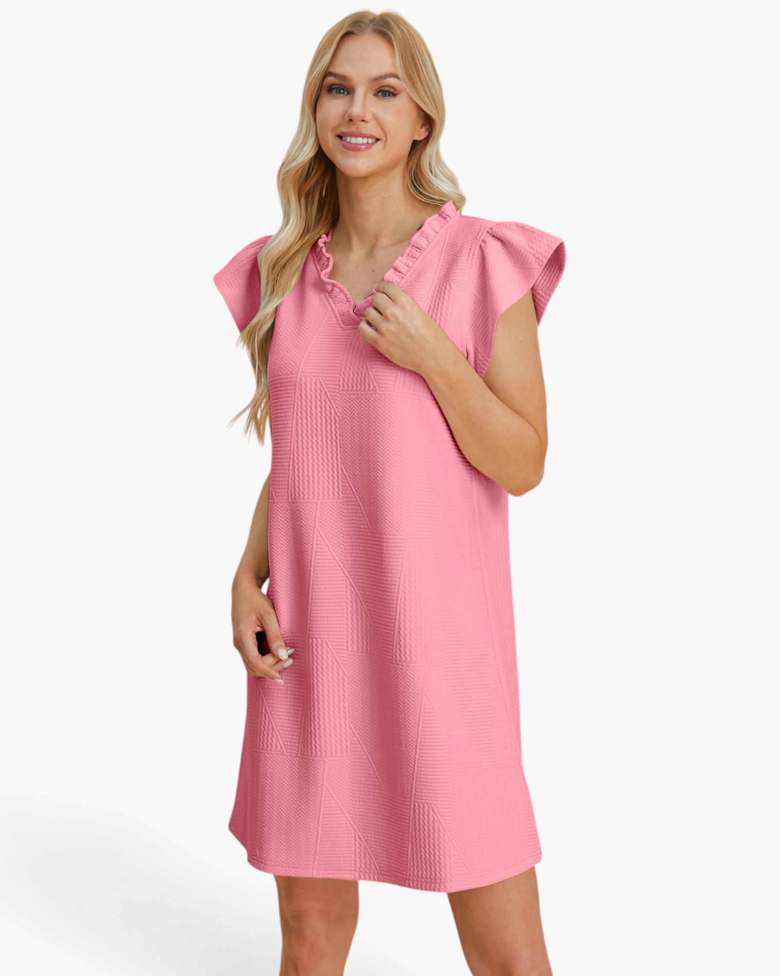 A woman modeling a pink short-sleeve dress with a textured waffle pattern, ruffled neckline, and flutter sleeves against a plain white background.