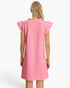 A woman viewed from the back wearing a pink textured dress with ruffled cap sleeves, photographed against a clean white studio background.