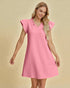 Woman wearing a pink dress with ruffled sleeves on a beige background