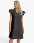 A woman modeling a dark charcoal gray textured dress with ruffled cap sleeves and a split neckline, photographed against a clean white studio background.