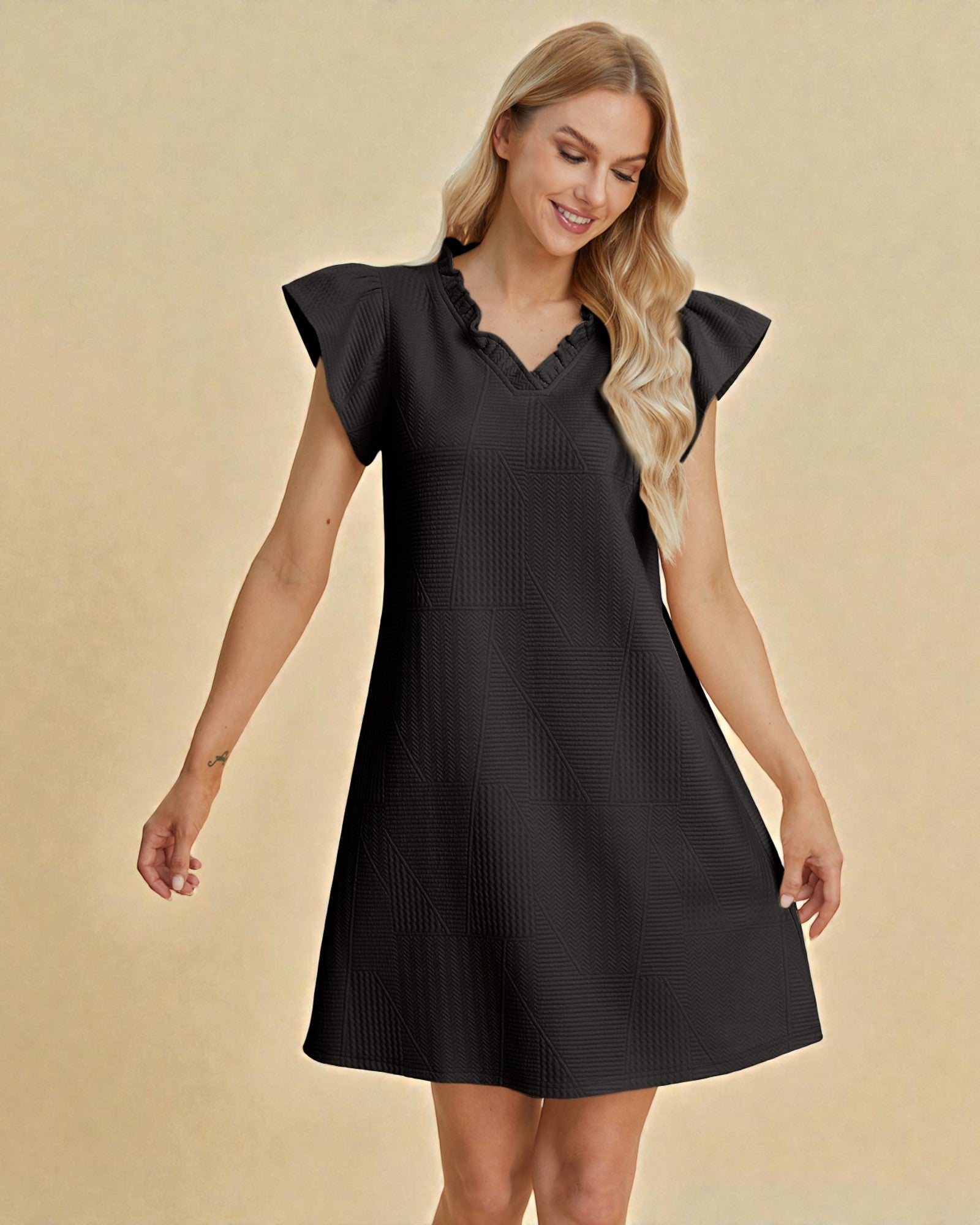 Woman wearing a black dress with ruffled sleeves on a beige background