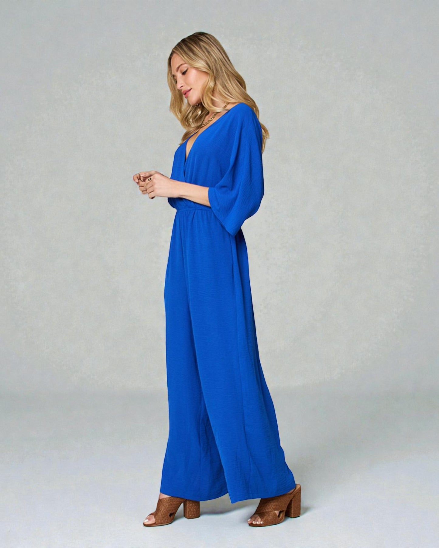 Woman wearing a blue jumpsuit on a plain background