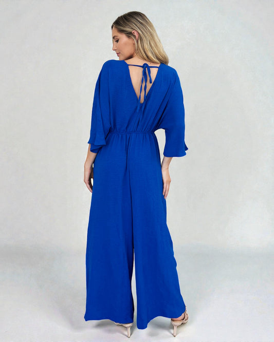 Woman wearing a blue jumpsuit with a plain background