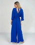 Woman wearing a blue jumpsuit with a plain background