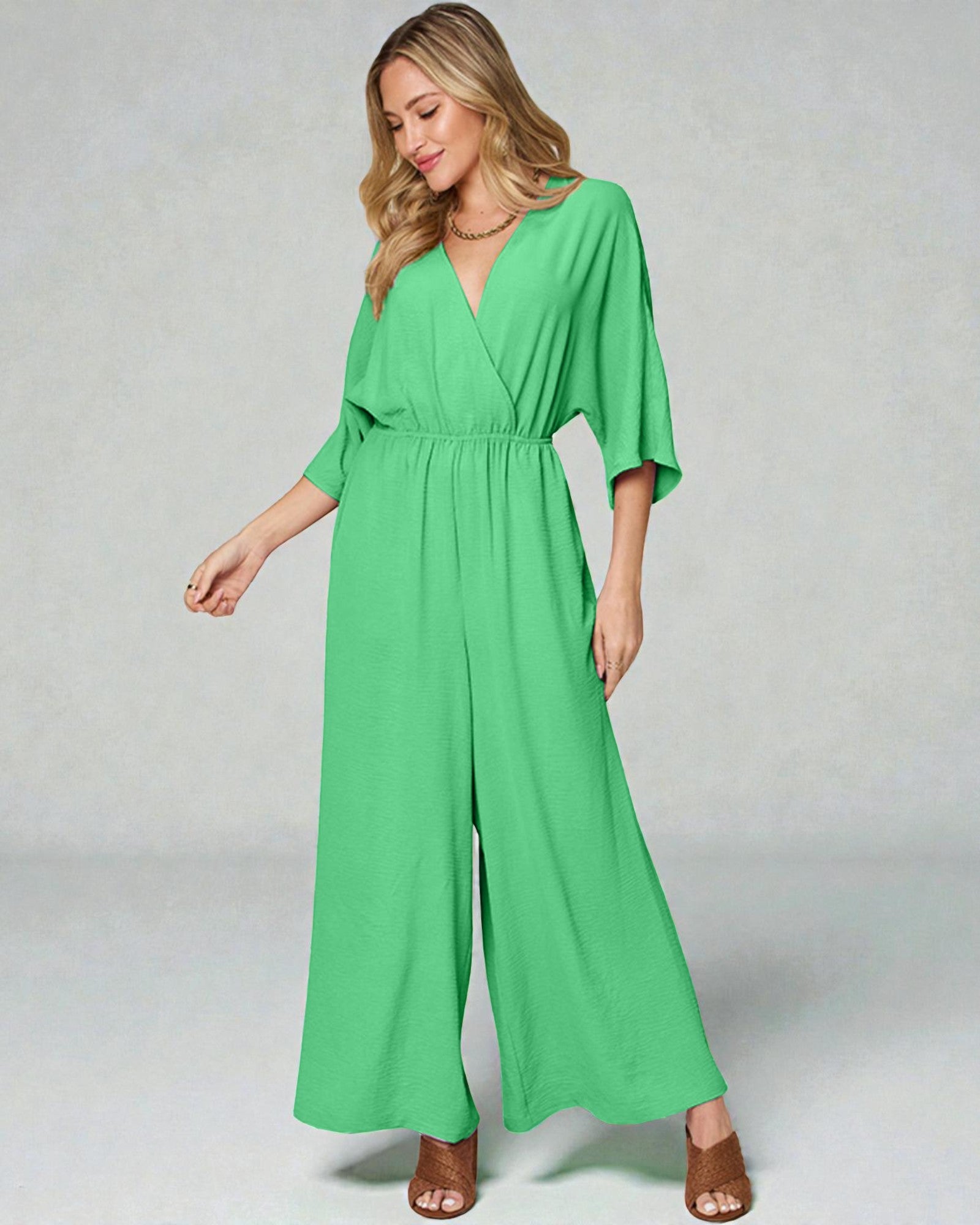 Woman wearing a green jumpsuit on a plain background