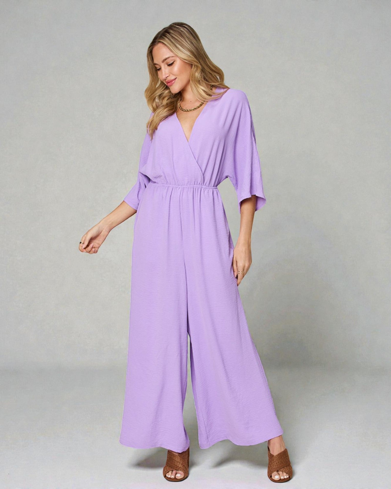 Woman wearing a purple jumpsuit on a plain background