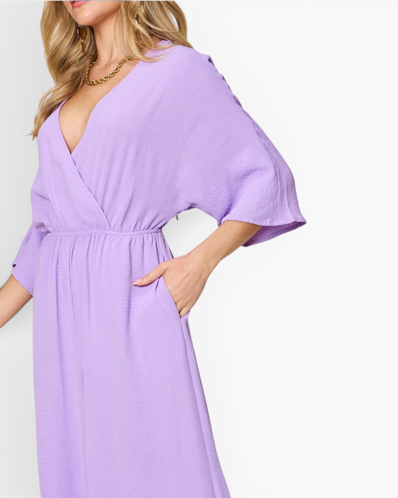 A woman wearing a light purple wrap-style midi dress with wide three-quarter sleeves and side pockets, shown against a plain white background.