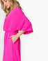 A woman wearing a bright hot pink wrap-style midi dress with wide flutter sleeves and a gathered waist, shown against a plain white studio background.