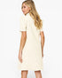 A woman with blonde hair is shown from the back wearing a short-sleeve cream-colored dress against a plain white background.