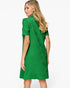 A woman modeling a bright green short-sleeve dress from the back, showing a textured geometric pattern, against a plain white studio background.