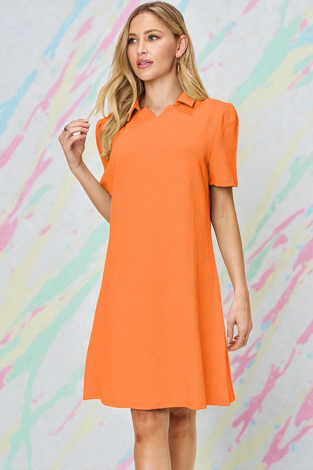 Woman wearing an orange dress against a colorful abstract background