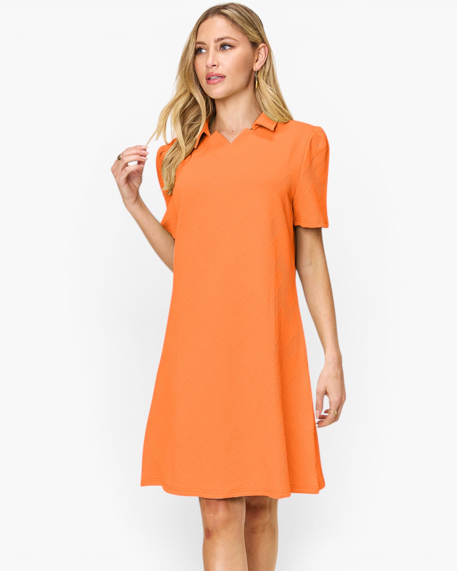 A woman modeling a bright orange short-sleeve polo dress against a plain white studio background.