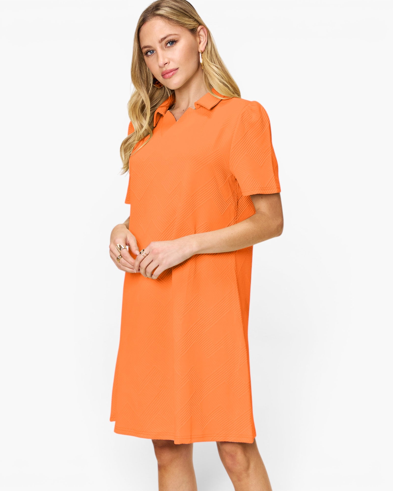 A woman modeling a short-sleeve collared shift dress in a bright orange color, photographed against a clean white studio background.