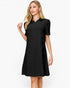 A woman modeling a black short-sleeve collared dress with a subtle textured pattern, set against a plain white studio background.