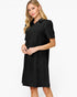 A woman modeling a short-sleeve black collared shift dress with a subtle textured pattern, set against a plain white studio background.