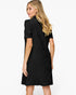 A woman with blonde hair is shown from the back wearing a short-sleeve black textured dress against a plain white background.