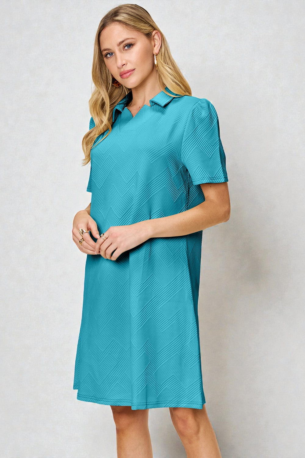 Woman wearing a teal dress against a plain background