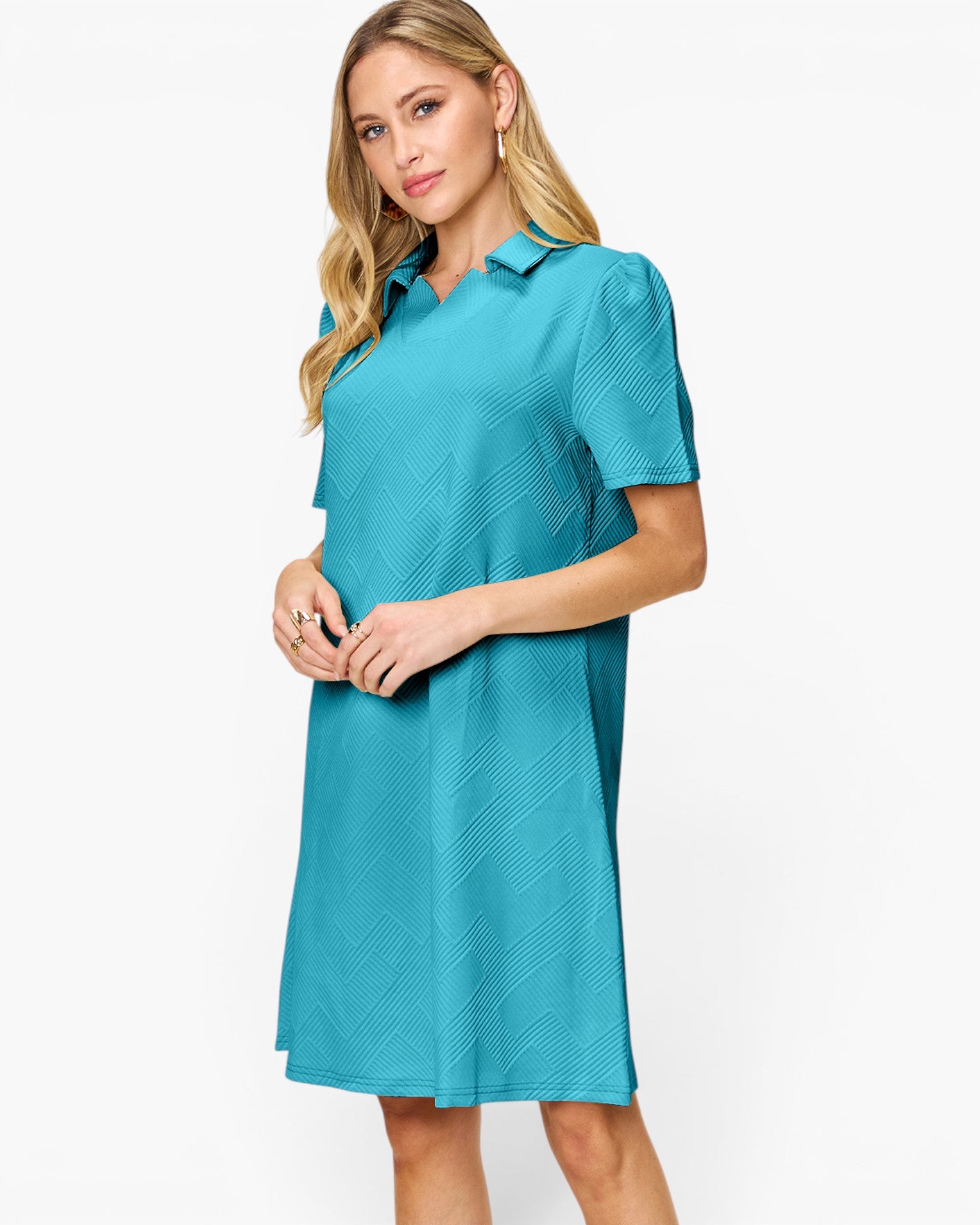 A woman modeling a short-sleeve collared shift dress in a bright turquoise blue color with a subtle textured pattern, set against a plain white studio background.