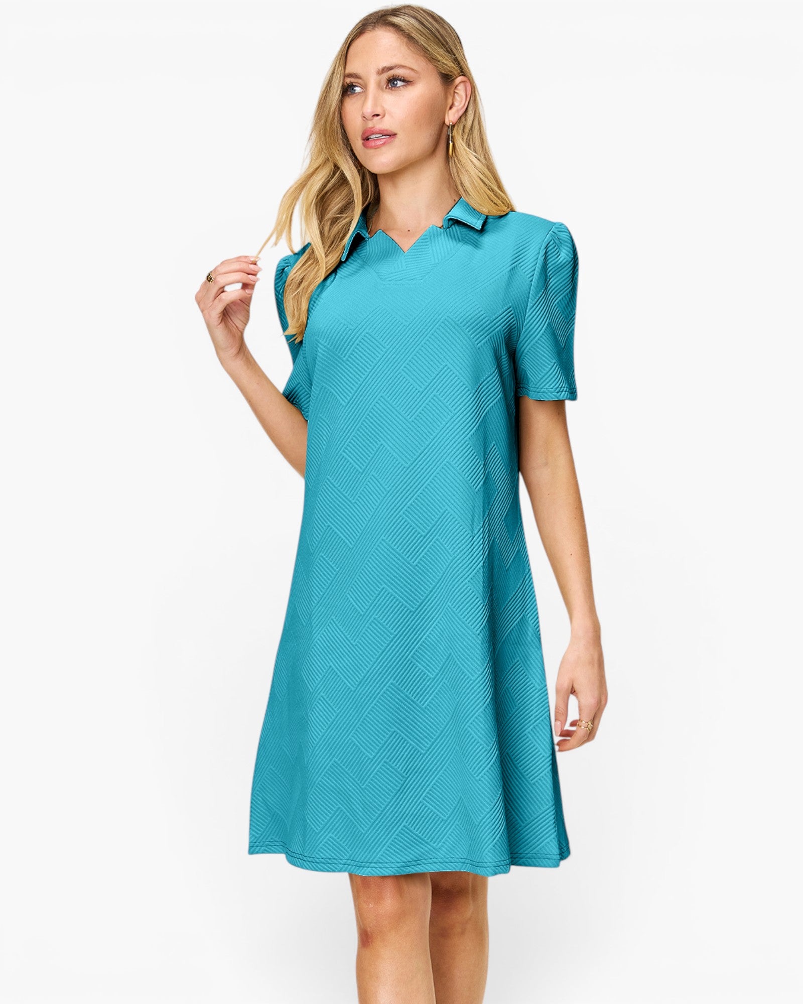 A woman modeling a short-sleeve collared shift dress in a bright turquoise blue color with a subtle textured geometric pattern, set against a plain white studio background.