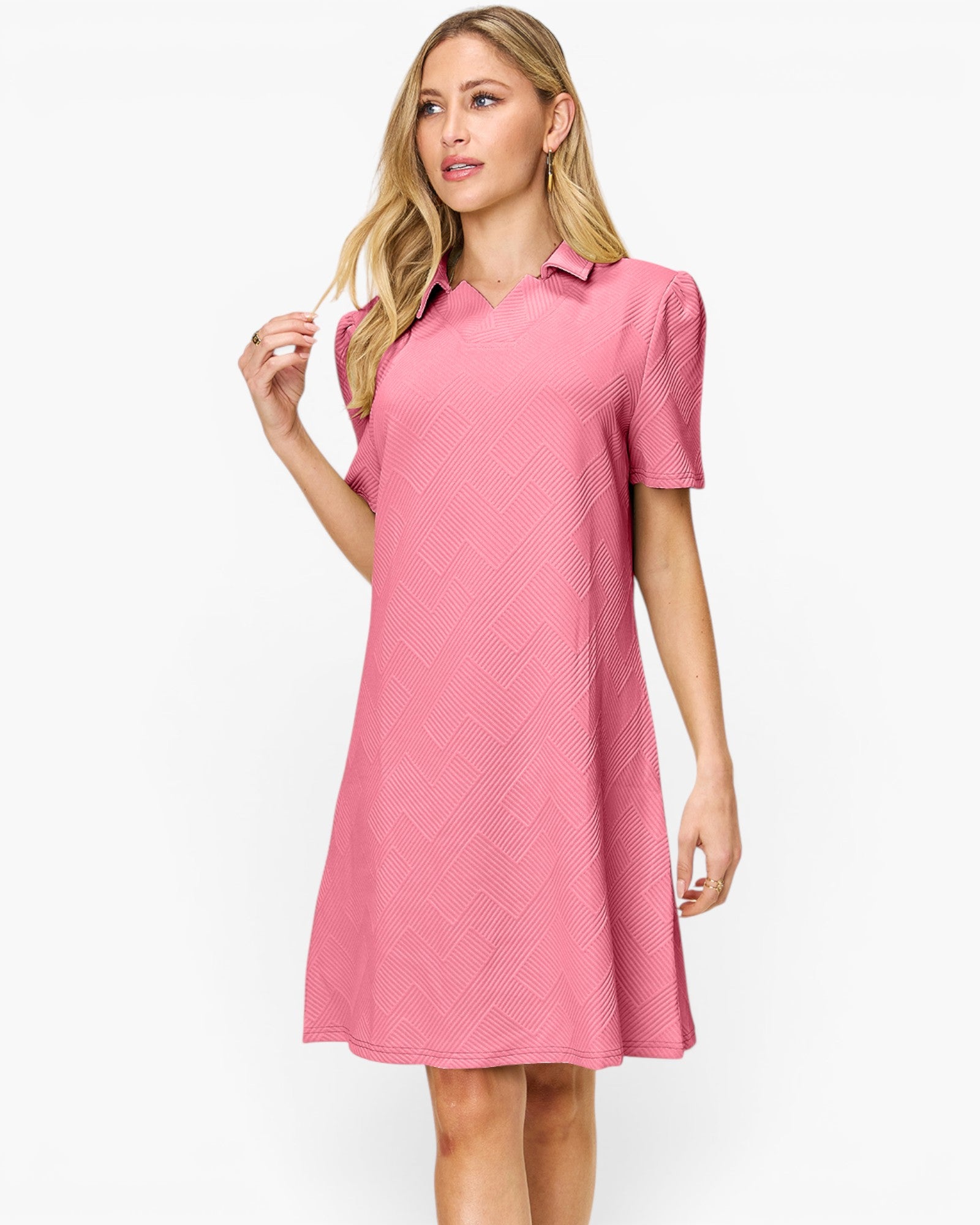 A woman modeling a pink short-sleeve collared dress with a subtle textured pattern, set against a plain white studio background.