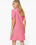 A woman modeling a pink short-sleeve dress from the back, showing a textured geometric pattern, against a plain white studio background.