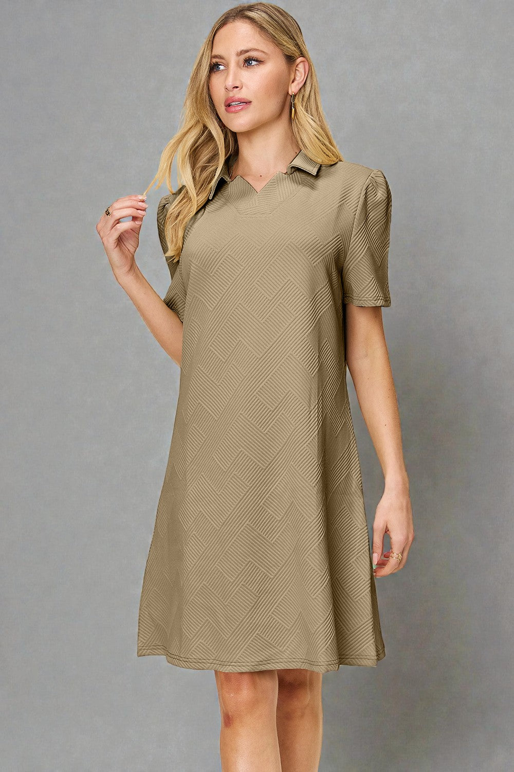 Woman wearing a beige dress with short sleeves against a gray background