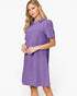 A woman modeling a short-sleeve purple collared shift dress with a subtle textured pattern, set against a plain white studio background.