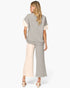 A woman shown from the back wearing a heather gray color-blocked knit set consisting of a short-sleeve top with cream-colored sleeve panels and matching wide-leg cropped pants, paired with beige block-heel sandals against a light gray studio background.